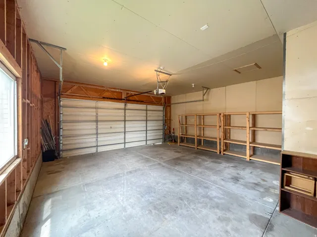 Spacious garage with a concrete floor, overhead lighting, and an automatic garage door opener