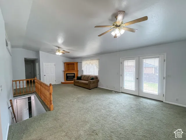 Spacious living area featuring a vaulted ceiling and green carpet flooring