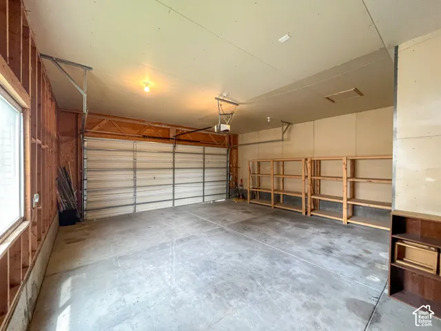 Spacious garage with a concrete floor, overhead lighting, and an automatic garage door opener
