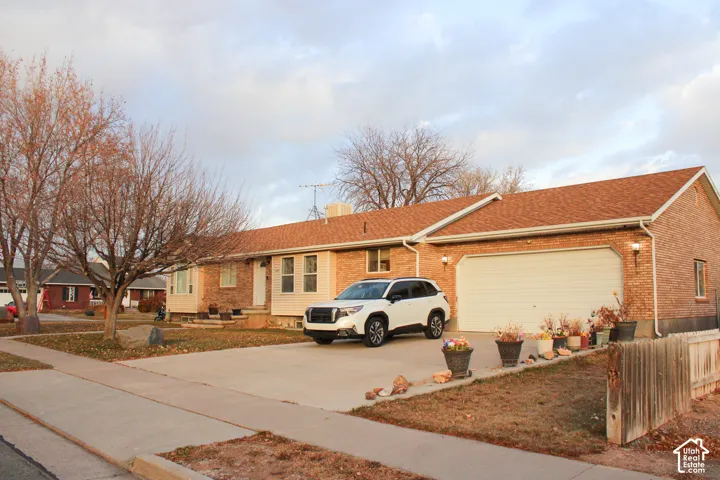 Brick facade residence with a two-car garage, concrete driveway, and mature landscaping