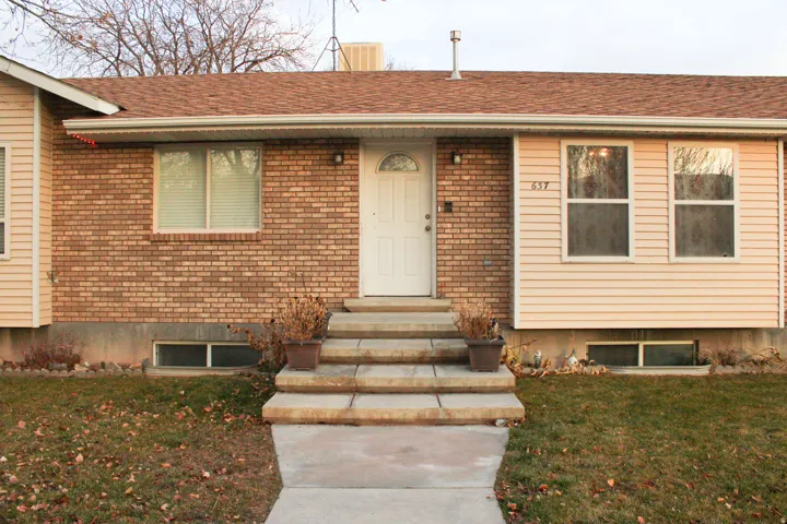 Brick and siding exterior featuring a central entry with a white door