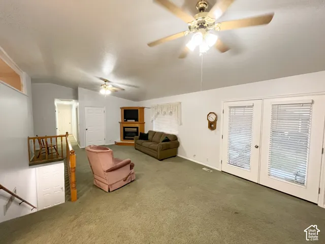Spacious living area featuring vaulted ceilings, two ceiling fans with integrated lighting, and a built-in media center with a fireplace