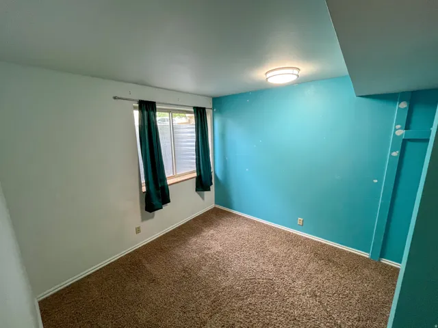 Carpeted room featuring a window with a wood sill, a flush mount ceiling light fixture, and baseboard trim