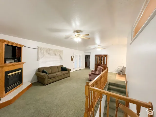 Spacious living area featuring a built-in entertainment center with a fireplace, vaulted ceilings, and ceiling fans