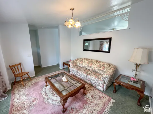 Living area featuring a chandelier light fixture, a decorative interior transom window, and wall-to-wall carpeting