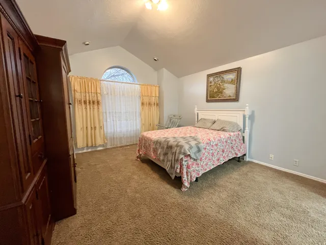 Vaulted ceiling bedroom with a large arched window
