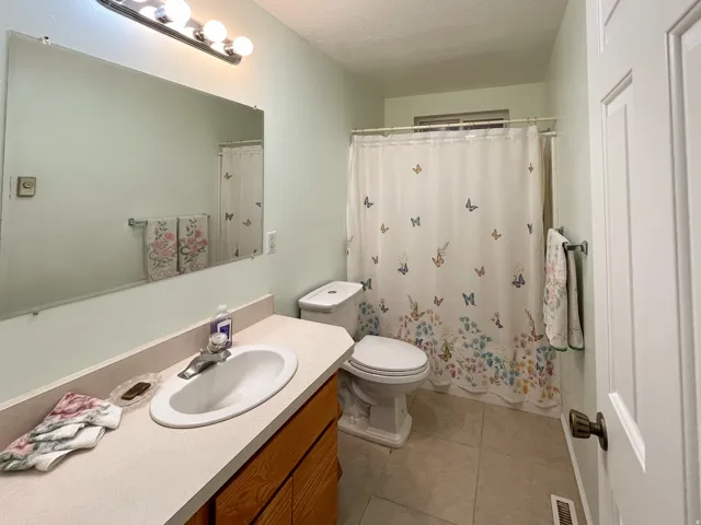 Bathroom featuring a vanity with a light-colored countertop and an integrated sink, a large wall-mounted mirror, and a toilet
