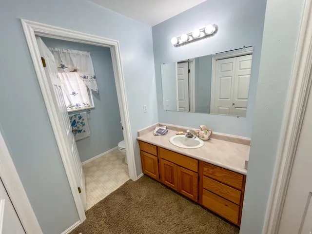 Bathroom vanity with a light-toned countertop, integrated sink, and wood-finish cabinetry