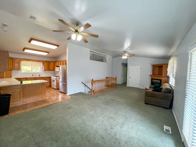 Open-concept living area featuring a kitchen with wood cabinetry, stainless steel appliances, and a central island
