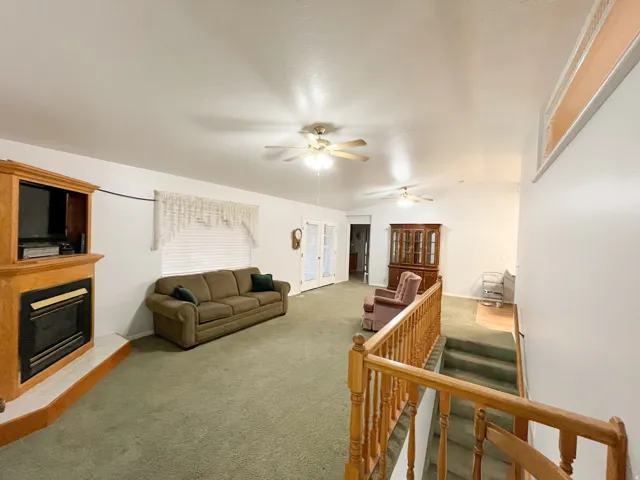 Spacious living area featuring a built-in entertainment center with a fireplace, vaulted ceilings, and ceiling fans