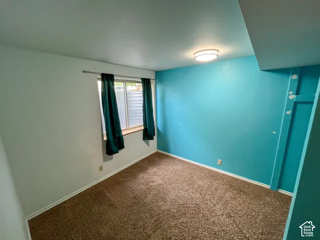 Carpeted room featuring a window with a wood sill, a flush mount ceiling light fixture, and baseboard trim