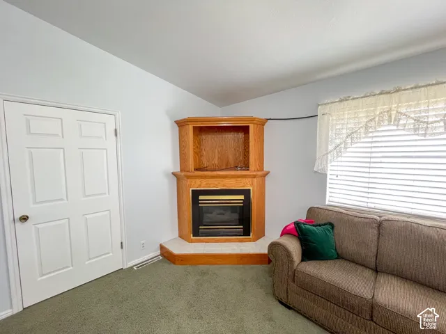 Corner fireplace with light wood-finish mantel and built-in shelving, featuring a tile hearth and a dark metal firebox