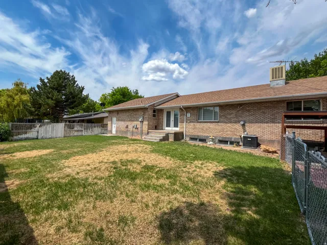 Brick exterior featuring a brown shingle roof, double French doors, and an air conditioning unit