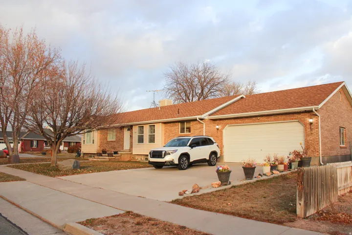 Brick facade residence with a two-car garage, concrete driveway, and mature landscaping