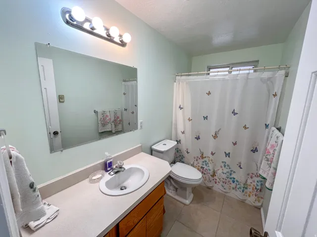 Full bathroom featuring a single vanity with a laminate countertop, undermount sink, and wood-finish cabinetry