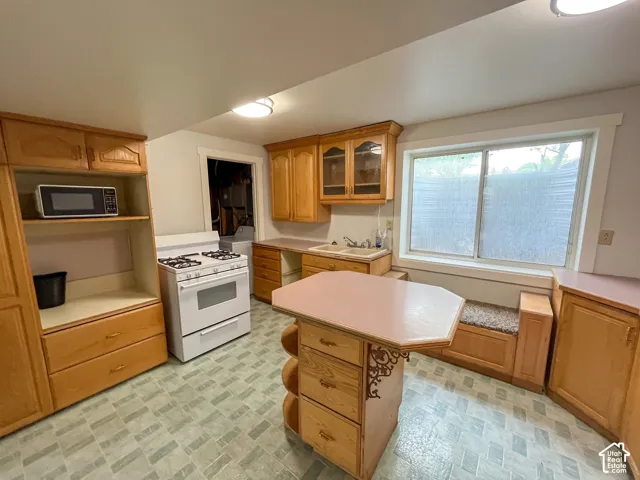 Kitchen featuring wood-finish cabinetry, a freestanding range, and a built-in window seat