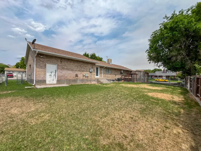 Spacious backyard featuring a brick exterior, mature trees, and a ground-level patio