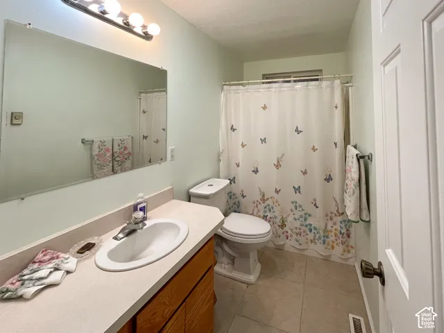 Bathroom featuring a vanity with a light-colored countertop and an integrated sink, a large wall-mounted mirror, and a toilet