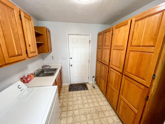 Utility room featuring extensive wood cabinetry, a built-in sink, and patterned flooring