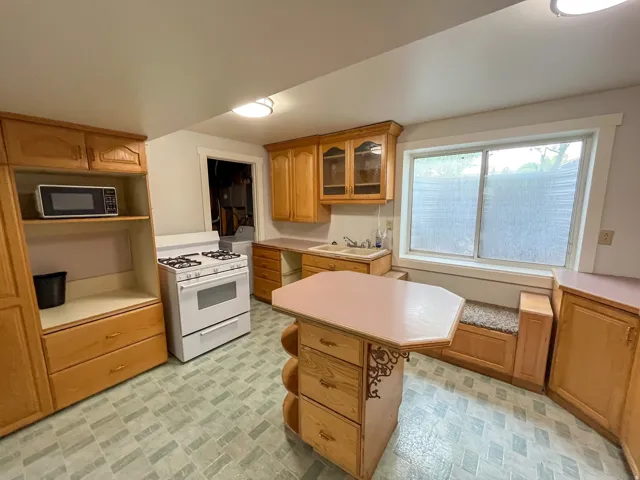 Kitchen featuring wood-finish cabinetry, a freestanding range, and a built-in window seat
