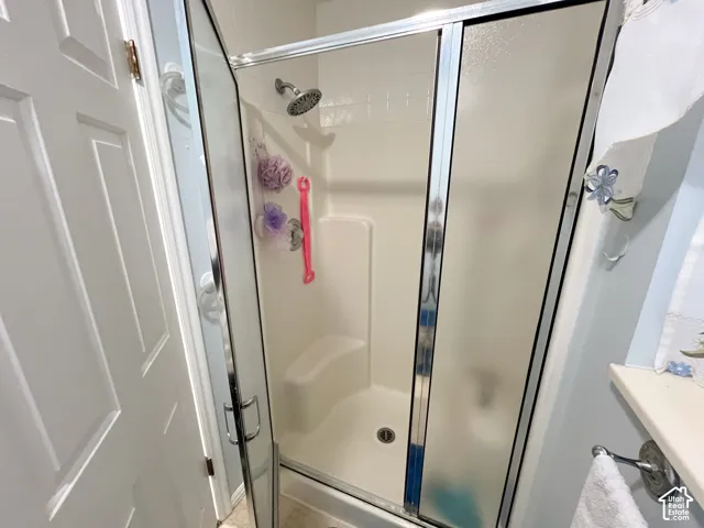Enclosed shower stall with a built-in seat, a chrome showerhead, and sliding frosted glass doors
