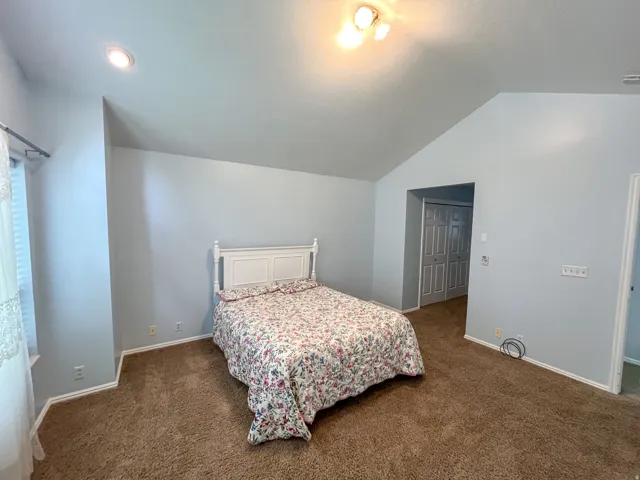 Vaulted ceiling room featuring light blue walls and brown carpeting