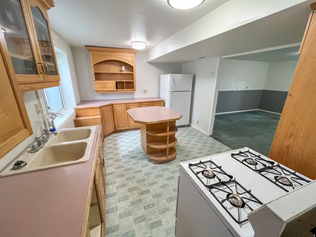 Kitchen featuring wood-finish cabinetry, a double basin sink, and a four-burner gas range