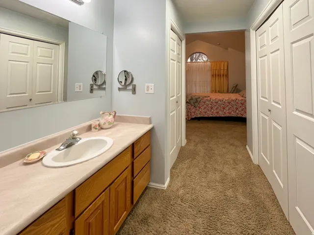 Bathroom vanity featuring an integrated sink with a chrome faucet, light wood-finish cabinetry, and a full-width wall mirror