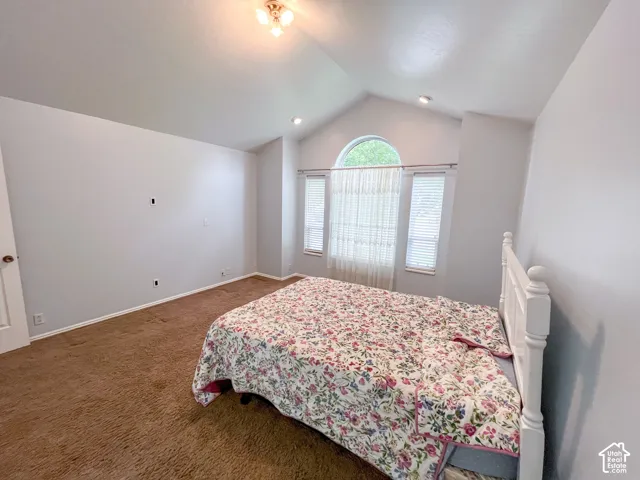 Vaulted ceiling bedroom featuring an arched transom window above two rectangular windows with blinds
