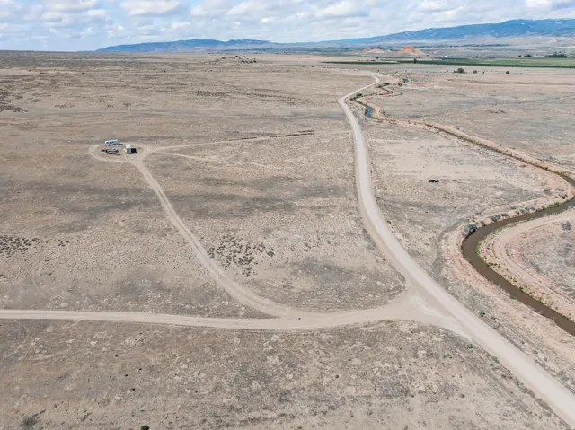 Expansive desert landscape featuring a winding dirt road and an irrigation canal