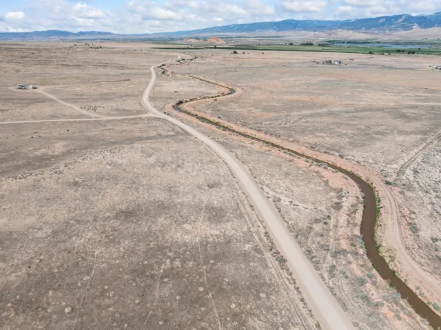 Expansive undeveloped land featuring a meandering dirt road and a natural waterway