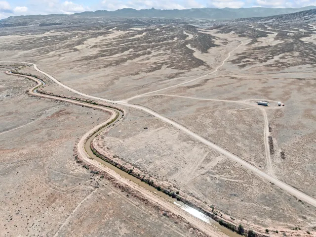 Expansive desert landscape featuring a winding irrigation canal and a network of unpaved roads
