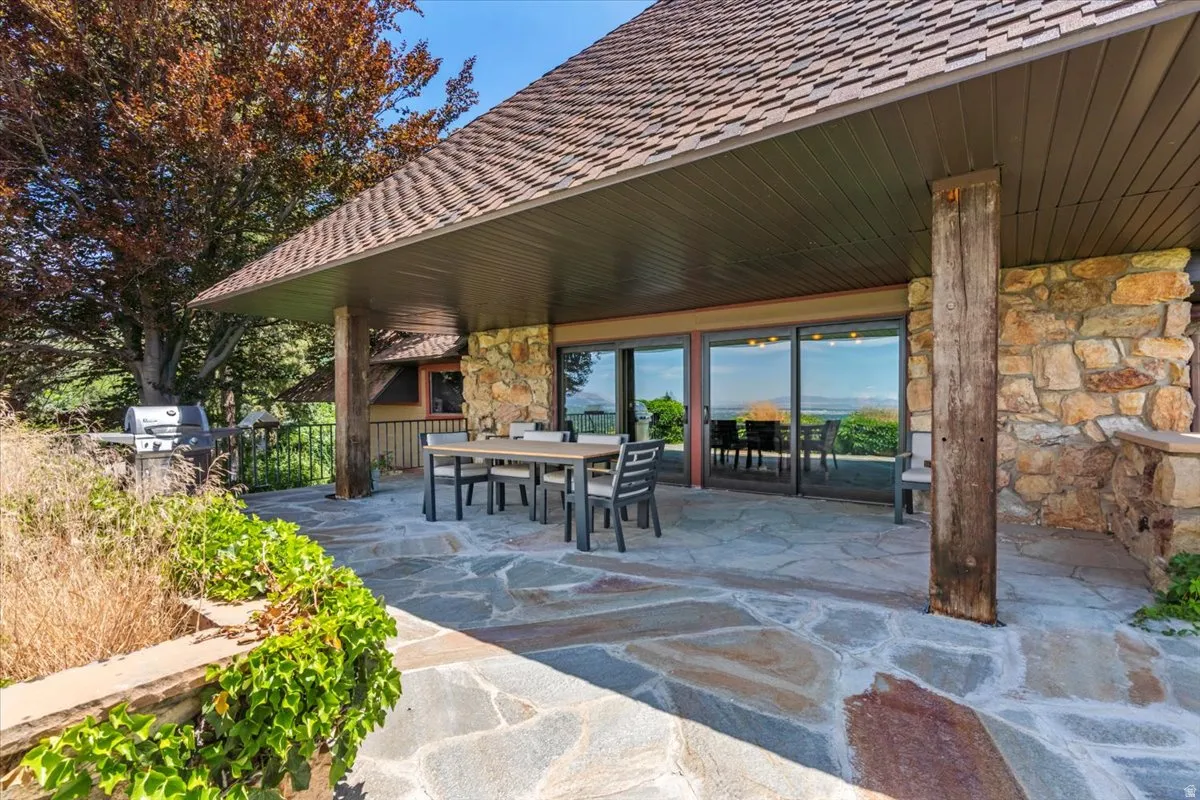 Expansive outdoor patio featuring flagstone flooring, a built-in outdoor grill, a stone accent wall, and a large roof overhang providing shade
