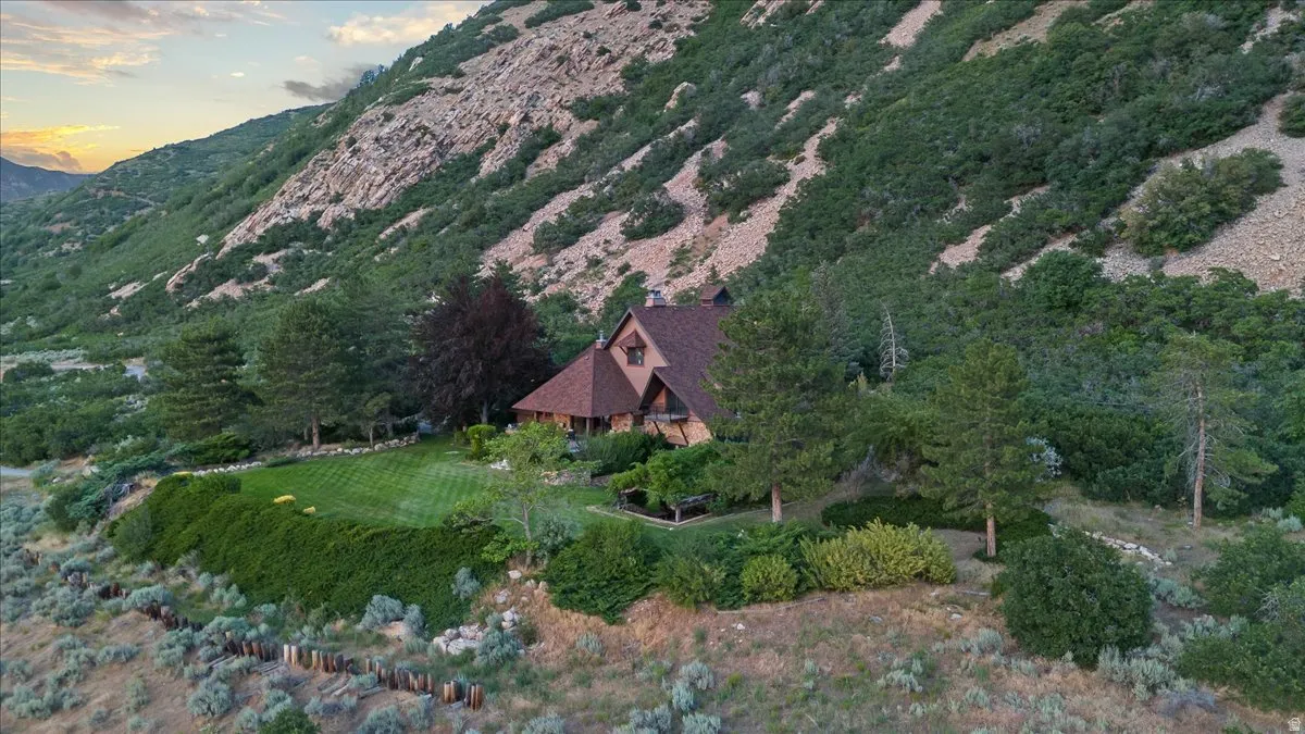 Mountain-side property featuring a multi-level structure with a gabled roof and a prominent, manicured lawn