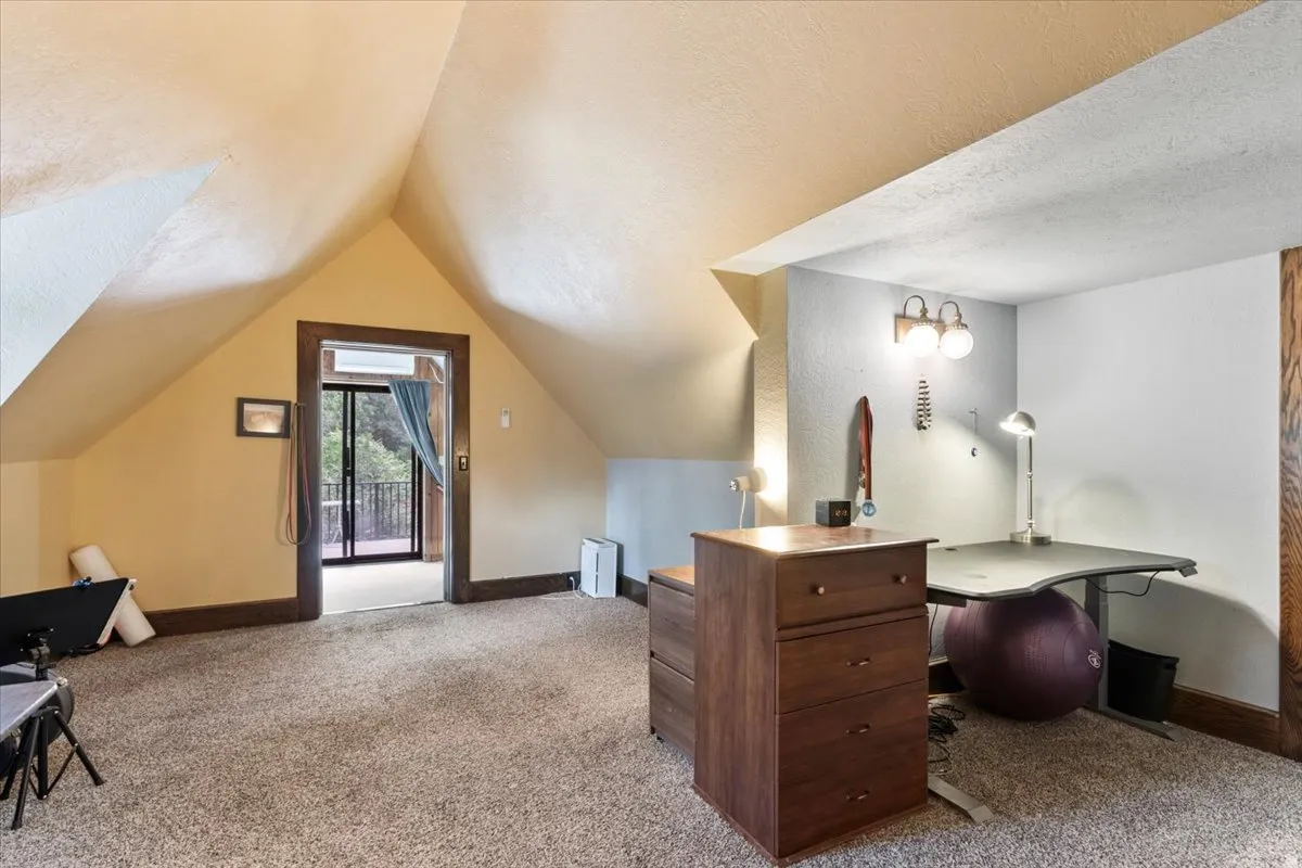 Attic space with sloped ceilings and carpet flooring