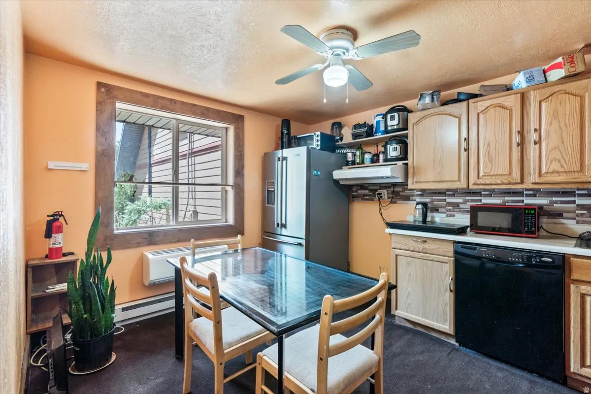 Kitchen featuring wood-finish cabinetry, a patterned tile backsplash, and a black dishwasher