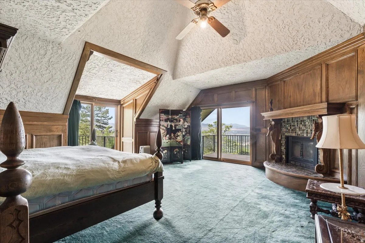 Vaulted ceiling room with wood paneling, sliding glass doors to exterior, a built-in fireplace with tile surround, and textured ceiling