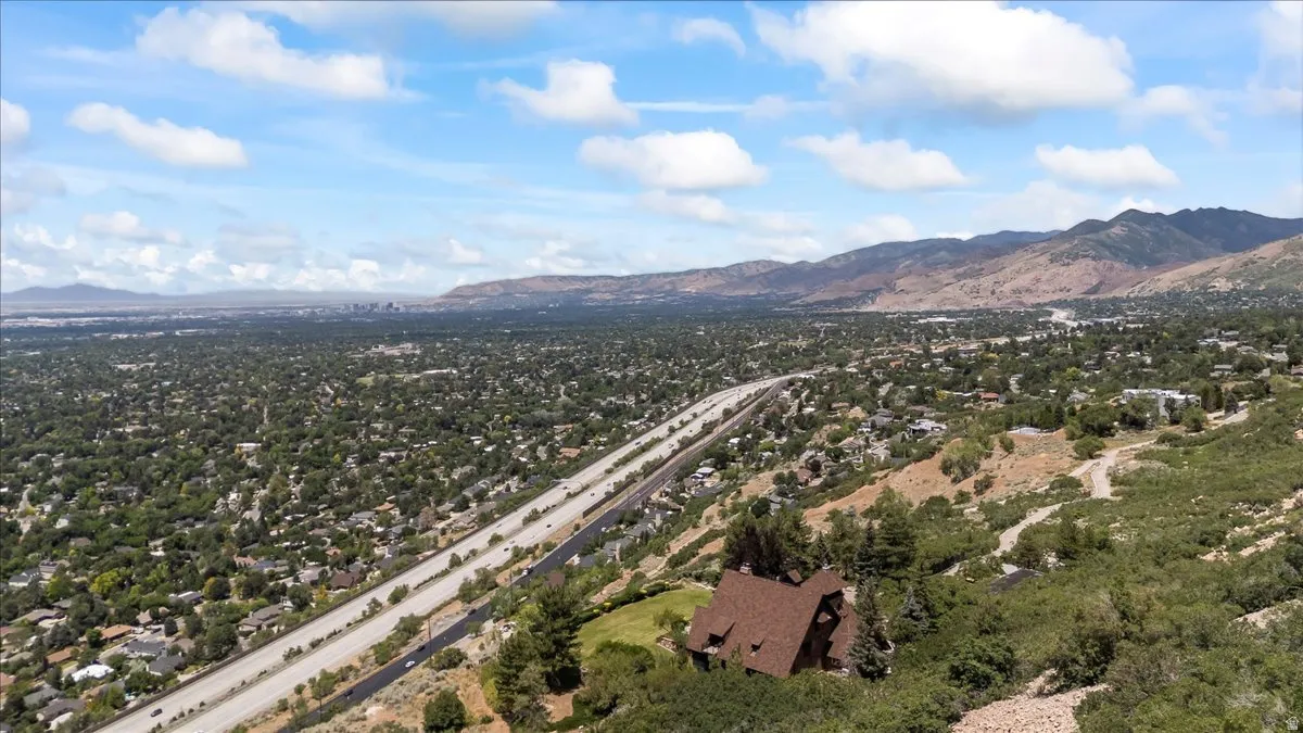 Mountainous terrain surrounding a large residential area with extensive tree coverage and a multi-lane highway