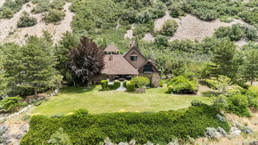 Stone and wood-sided residence featuring a multi-level roofline and extensive landscaping