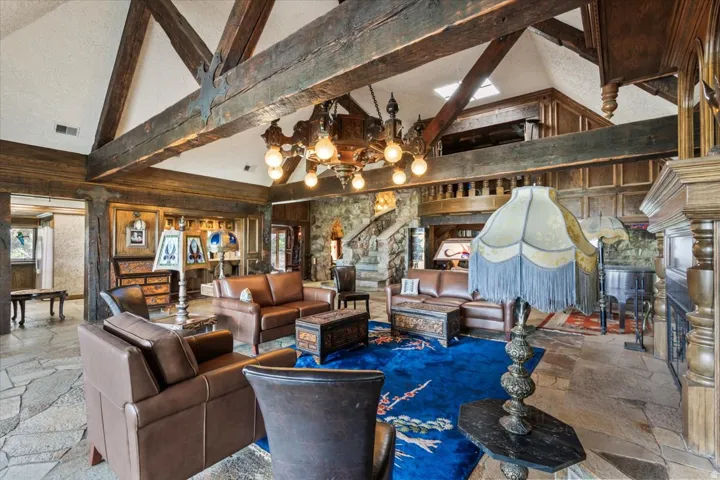 Grand living area featuring exposed wood beams, vaulted ceilings, and flagstone flooring