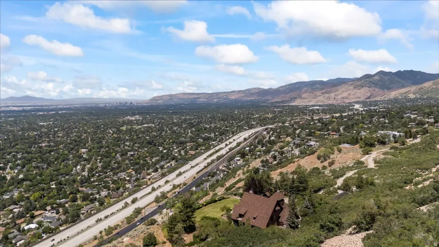Mountainous terrain surrounding a large residential area with extensive tree coverage and a multi-lane highway