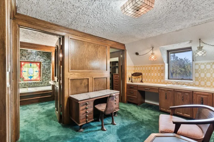 Spacious interior featuring wood-paneled walls, an integrated vanity with a basin sink, and a built-in desk