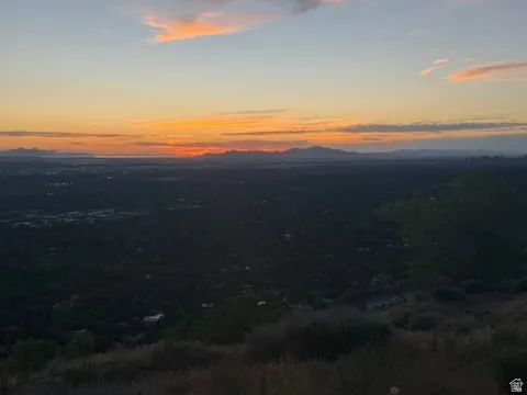 Panoramic landscape featuring distant city lights under a vibrant sunset sky