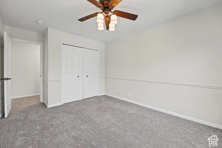 Wall-to-wall carpeting, bi-fold closet doors, ceiling fan with integrated lighting, and paneled wainscoting