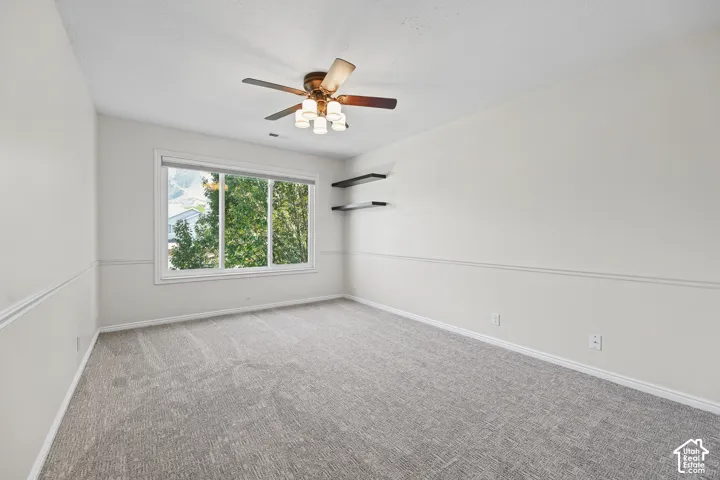 Neutral wall finishes, recessed window, wall trim, ceiling fan light fixture, and gray textured carpet