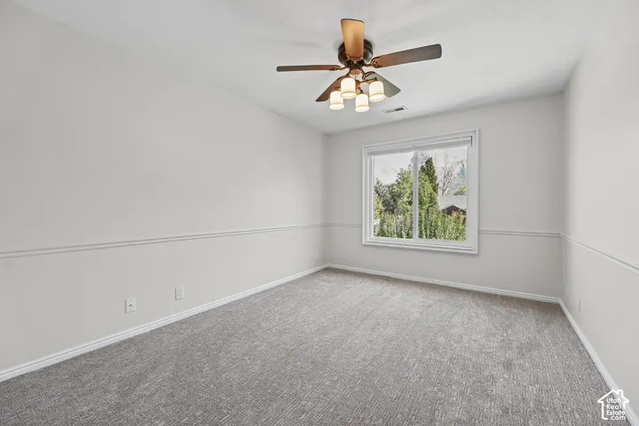 Gray carpet flooring, white walls, and a multi-light ceiling fan