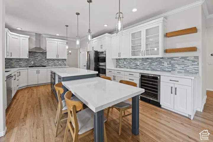 Gourmet kitchen with white cabinetry, stainless steel appliances, dual islands, and wood-finish flooring