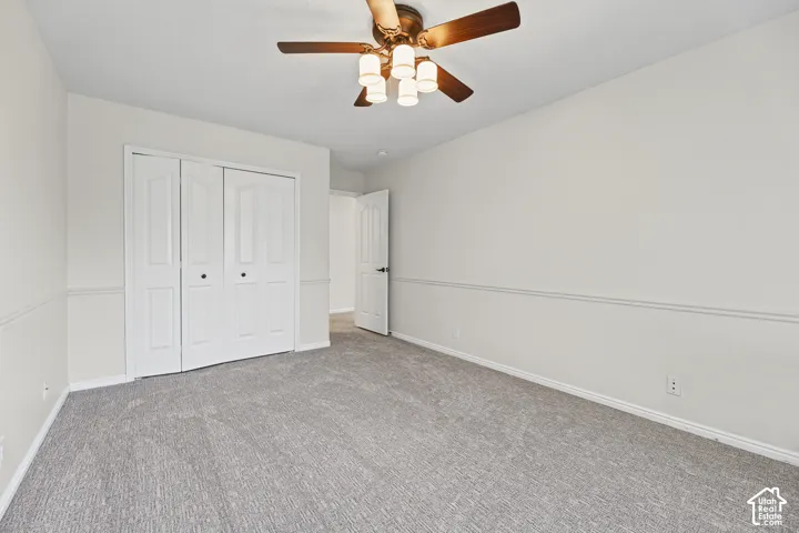 Light gray carpeting throughout, white walls, and a ceiling fan with integrated lighting