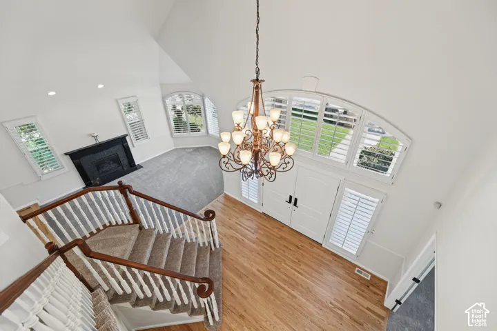 Hardwood flooring, wrought iron chandelier, and a curved staircase with carpeted treads