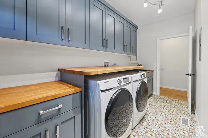 Extensive cabinetry, wood-finish countertops, geometric-patterned floor tiling, and track lighting